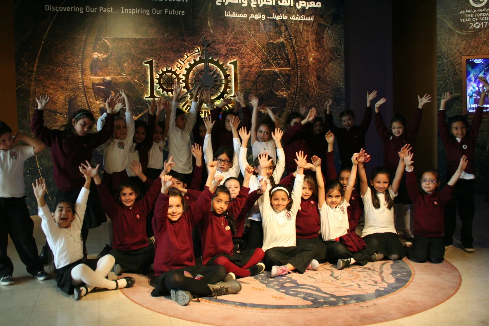 Children raising their hands during a group visit to a 1001 Inventions exhibition.